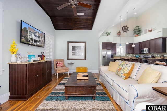 living area with baseboards, wood ceiling, ceiling fan, wood finished floors, and high vaulted ceiling