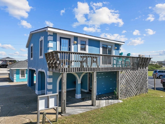 rear view of property with a lawn, a deck, and stucco siding