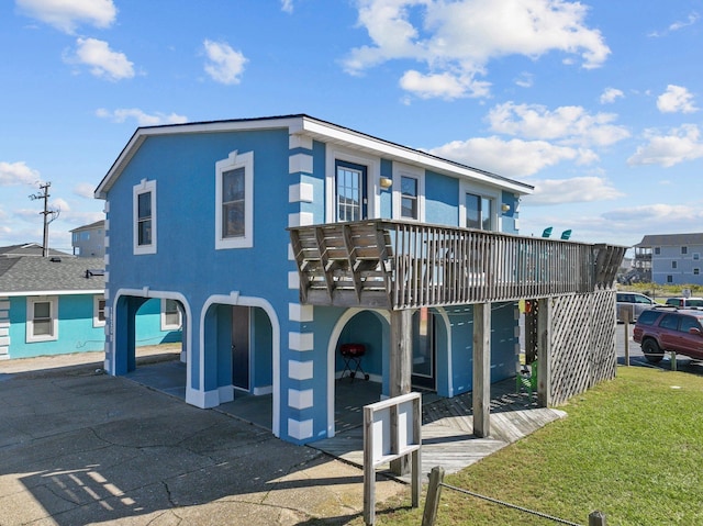 view of front of home with a wooden deck, a front lawn, and stucco siding