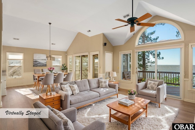 living room with a wainscoted wall, a water view, visible vents, and wood finished floors