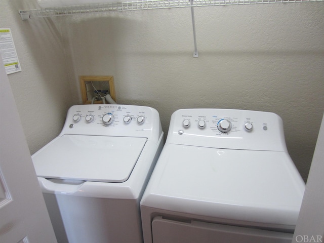 laundry area featuring laundry area, a textured wall, and separate washer and dryer