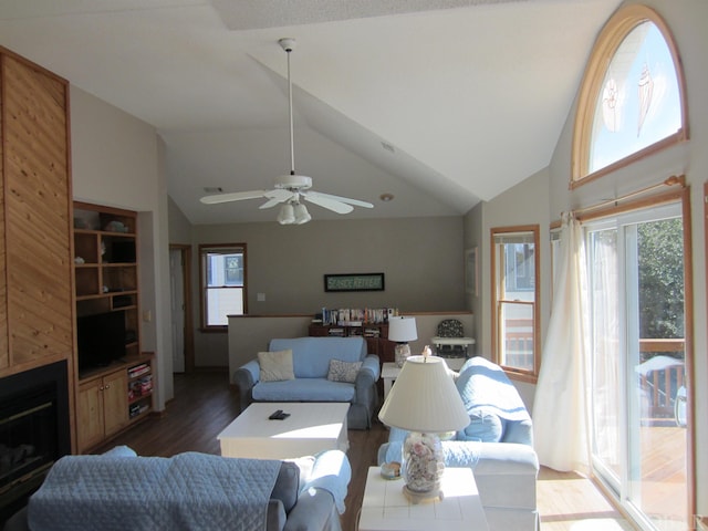 living room featuring dark wood-style floors, a fireplace, high vaulted ceiling, and a ceiling fan