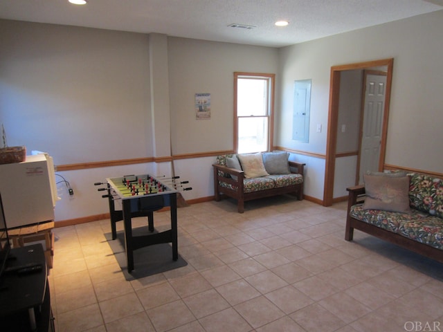 living area featuring recessed lighting, electric panel, a textured ceiling, and baseboards