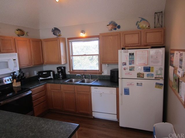 kitchen with dark countertops, white appliances, and a sink