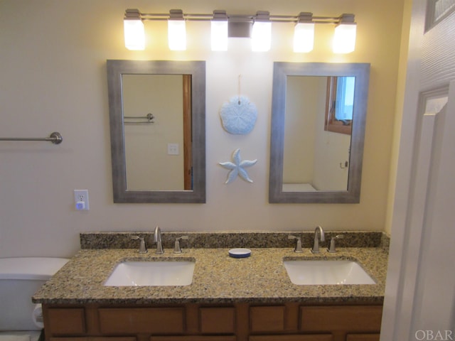 bathroom featuring toilet, double vanity, and a sink