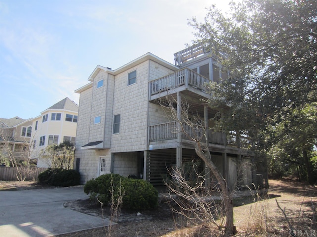 view of side of home featuring driveway and a balcony