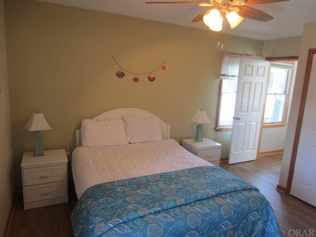 bedroom with dark wood-style floors, a ceiling fan, and baseboards