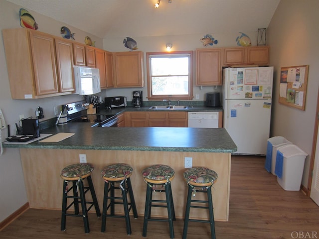 kitchen featuring dark countertops, white appliances, a peninsula, and a sink