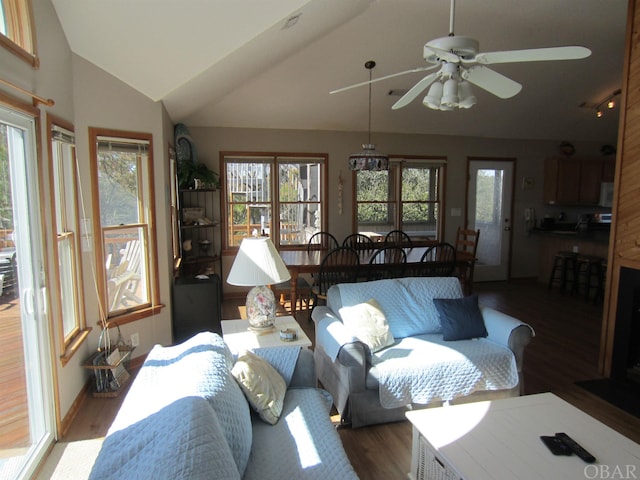 living area with a healthy amount of sunlight, dark wood-style floors, and vaulted ceiling