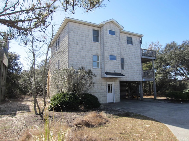 view of side of home featuring concrete driveway and a balcony