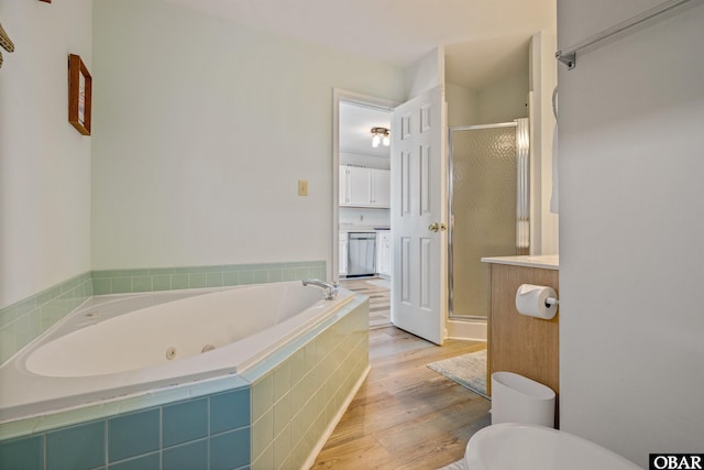 bathroom featuring a tub with jets, a stall shower, wood finished floors, and toilet