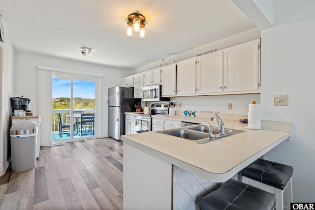 kitchen featuring light countertops, appliances with stainless steel finishes, a sink, and white cabinets