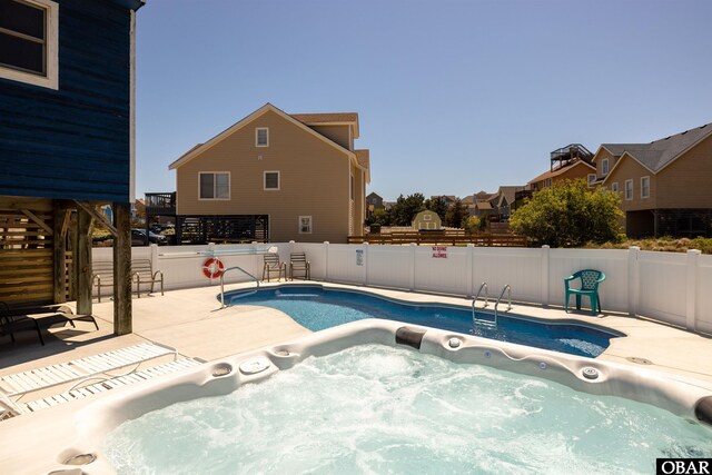 view of pool featuring a hot tub, a residential view, and a fenced backyard