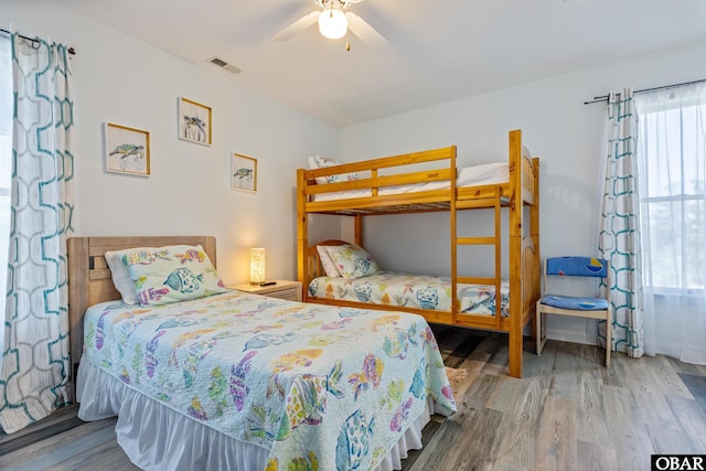 bedroom featuring wood finished floors, visible vents, and a ceiling fan