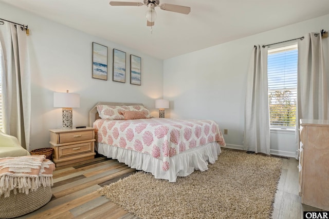 bedroom featuring light wood finished floors, a ceiling fan, and baseboards