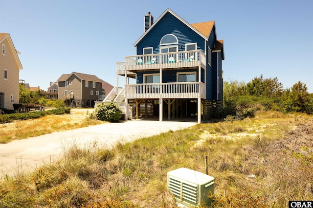 back of house with a carport, a chimney, and a balcony