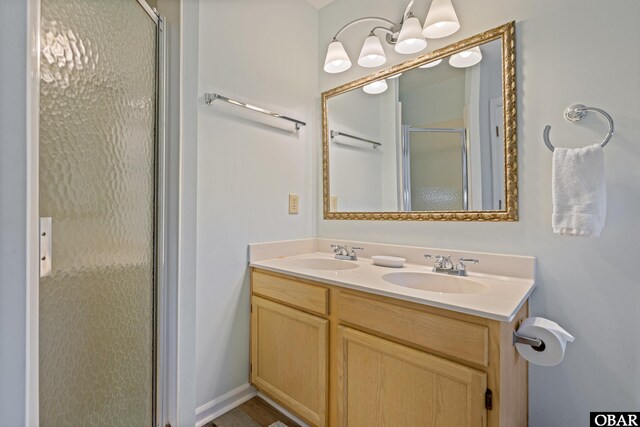 full bathroom with double vanity, a stall shower, and a sink