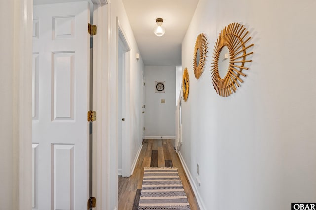 corridor featuring baseboards and wood finished floors