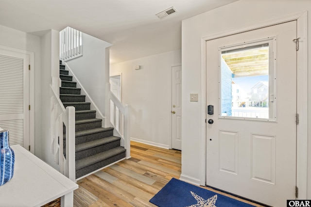 entrance foyer with light wood-style floors, baseboards, stairs, and visible vents