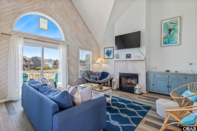 living room with light wood-type flooring, a fireplace, and high vaulted ceiling