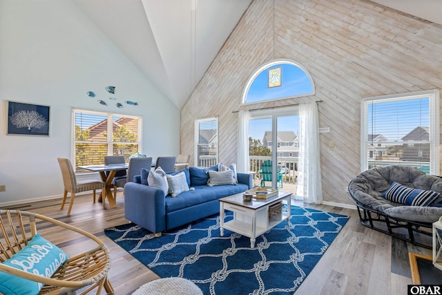 living room with high vaulted ceiling, light wood-type flooring, and baseboards