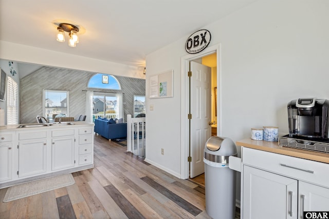 kitchen featuring open floor plan, light wood-type flooring, a sink, and white cabinets