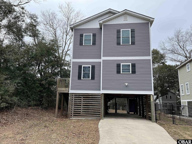 beach home with a carport, concrete driveway, and stairway