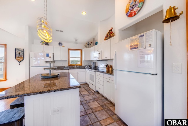 kitchen featuring a sink, white appliances, a kitchen island, and white cabinetry