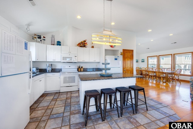 kitchen with white appliances, a kitchen island, white cabinetry, and pendant lighting