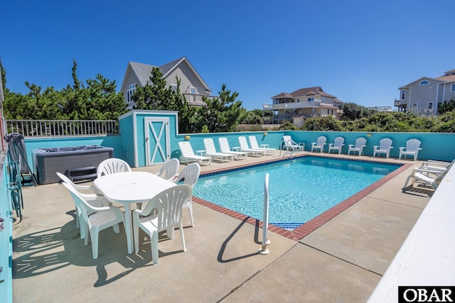 community pool with a patio area and fence