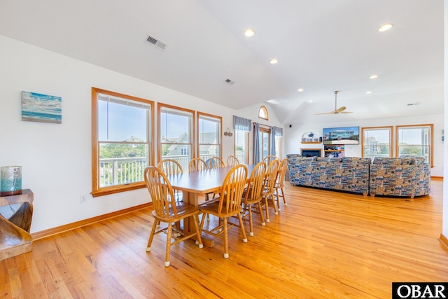 dining area with a wealth of natural light, visible vents, vaulted ceiling, and light wood-style flooring