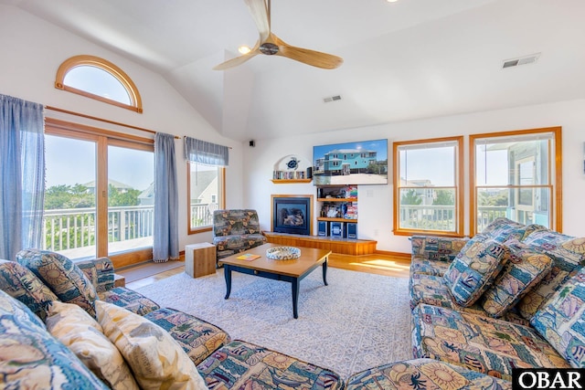 living area with vaulted ceiling, a wealth of natural light, wood finished floors, and visible vents