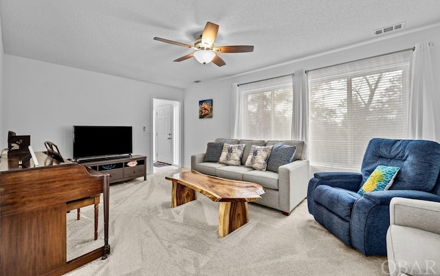 living room with a wealth of natural light, visible vents, light carpet, and a textured ceiling