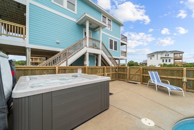 view of patio / terrace with stairway, fence, and a hot tub