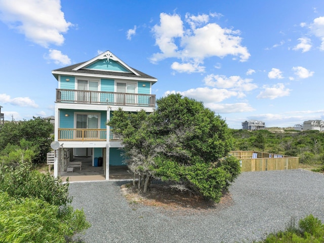 coastal home with a carport, a balcony, and driveway