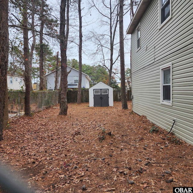 view of yard featuring a storage shed, fence, and an outdoor structure