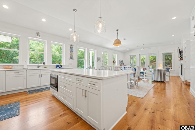 197 Wax Myrtle Trl Lot # 15R, Southern Shores, NC 27949 - kitchen with vaulted ceiling, light countertops, light wood-type flooring, white cabinetry, and decorative light fixtures