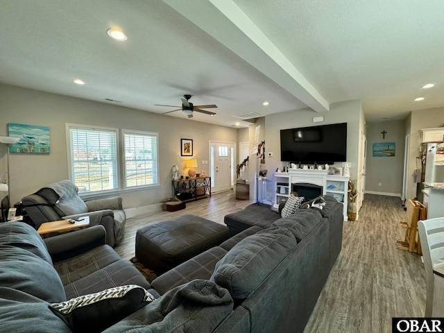 living area with baseboards, wood finished floors, and ceiling fan