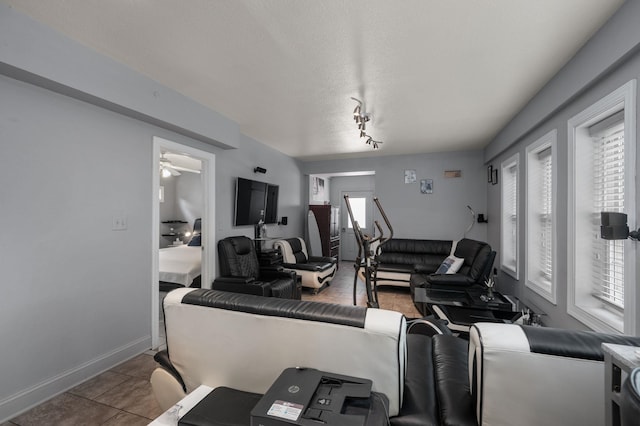 tiled living area featuring a textured ceiling and baseboards