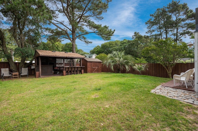 view of yard with a fenced backyard, a shed, outdoor dry bar, and an outbuilding