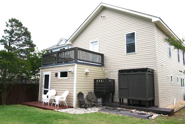 rear view of property with a balcony, fence, and a lawn