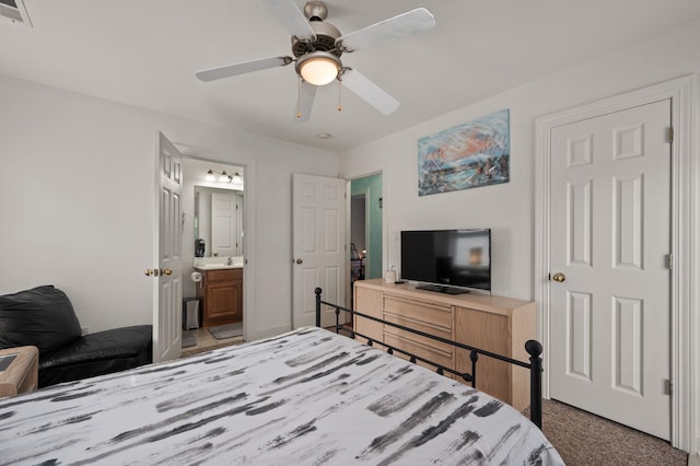 carpeted bedroom with connected bathroom, visible vents, and a ceiling fan