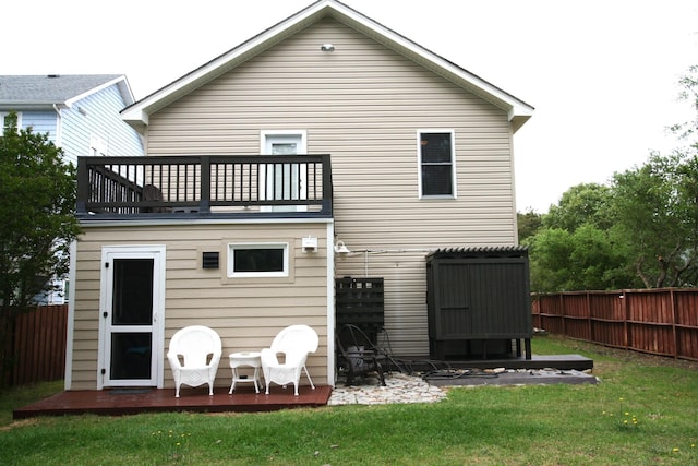 back of house featuring a balcony, fence, and a yard