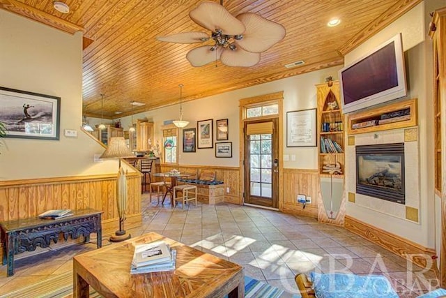 living area featuring wooden ceiling, light tile patterned floors, a fireplace, and a wainscoted wall