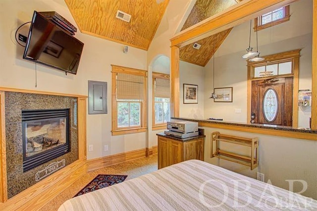 bedroom with visible vents, a glass covered fireplace, high vaulted ceiling, electric panel, and baseboards