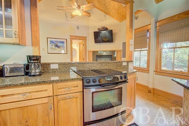 kitchen with ceiling fan, glass insert cabinets, stainless steel electric range, stone counters, and a fireplace