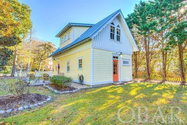 back of property with board and batten siding, a lawn, and fence