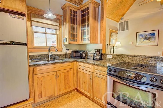 kitchen featuring visible vents, stainless steel electric range oven, glass insert cabinets, freestanding refrigerator, and a sink