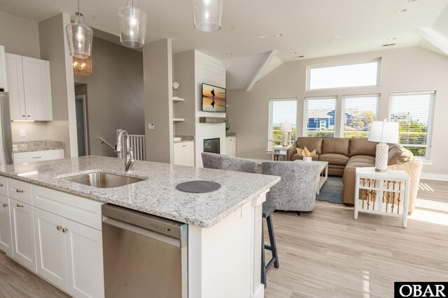 kitchen with a sink, white cabinets, open floor plan, dishwasher, and a center island with sink