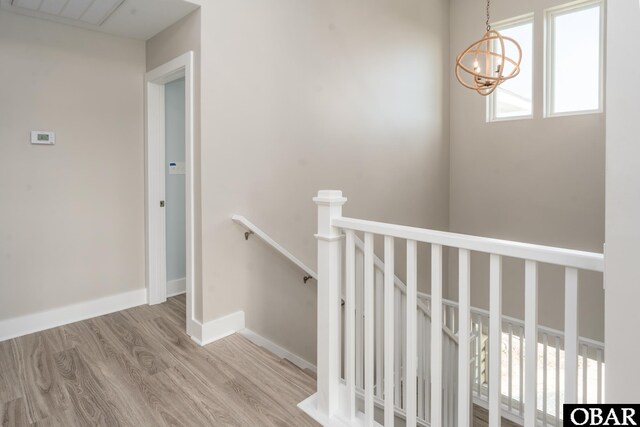 stairs featuring a chandelier, wood finished floors, and baseboards